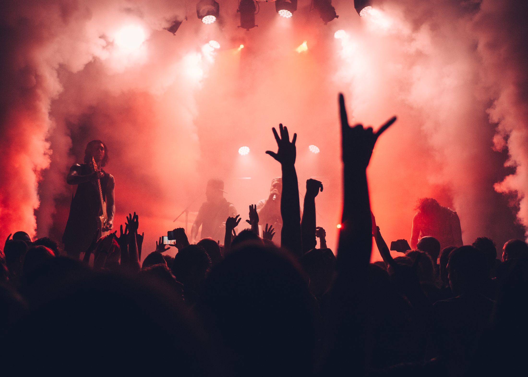 A performer facing a live audience under stage lighting