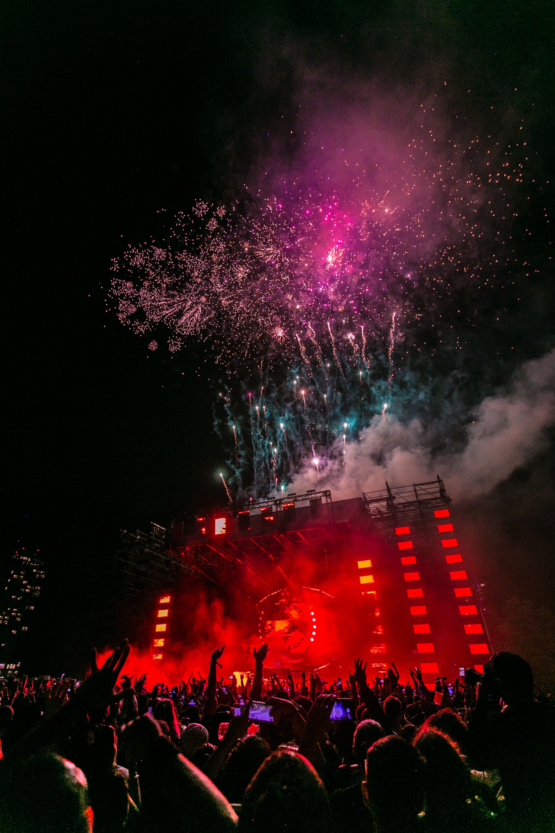 Live festival stage and crowd beneath fireworks